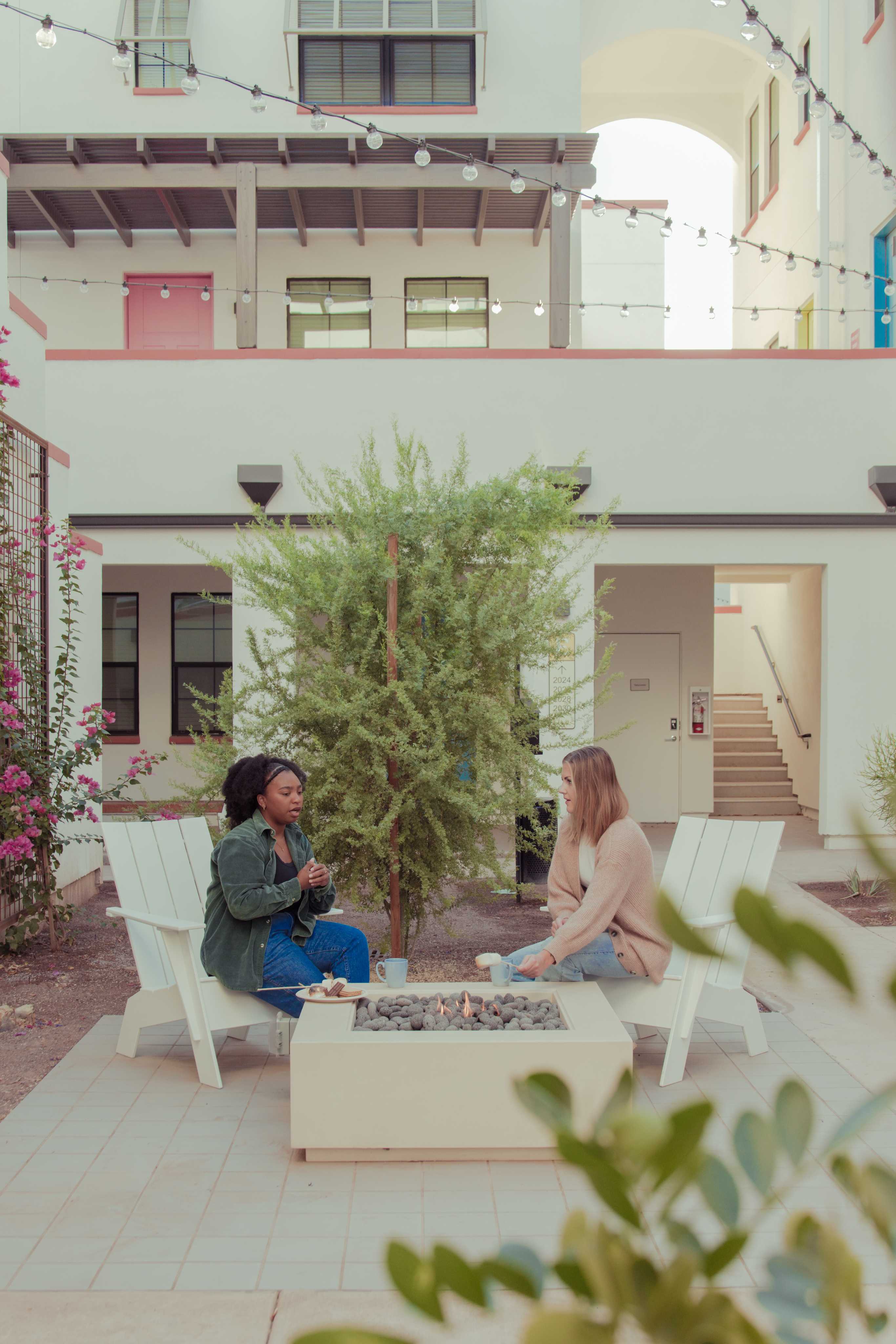 Two women sitting in chairs by fire pit