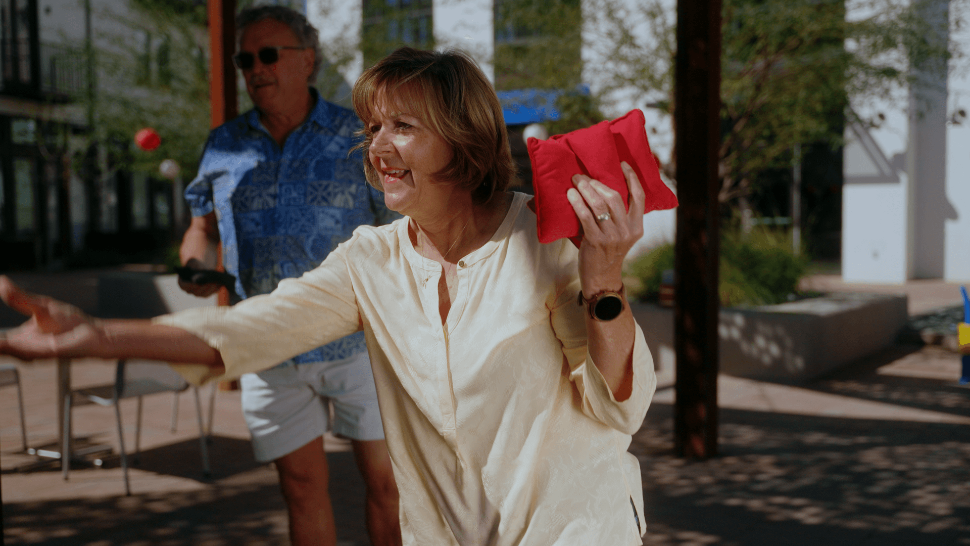 Woman throwing underhand cornhole in outdoor plaza